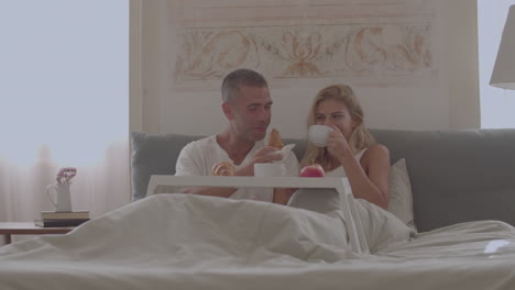 happy caucasian couple having breakfast in bed at home