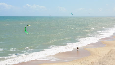 Aerial-view-of-people-practing-kite-surf-and-small-village-around,-Cumbuco,-Ceara,-Brazil