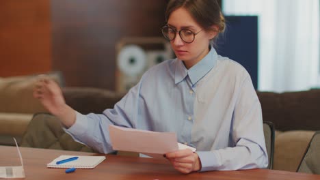 mujer contable contable que gestiona los gastos financieros, calcula las facturas o los impuestos, escribe con pluma en el escritorio