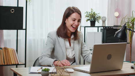 business woman works on laptop shocked by sudden victory game winning good news at home office