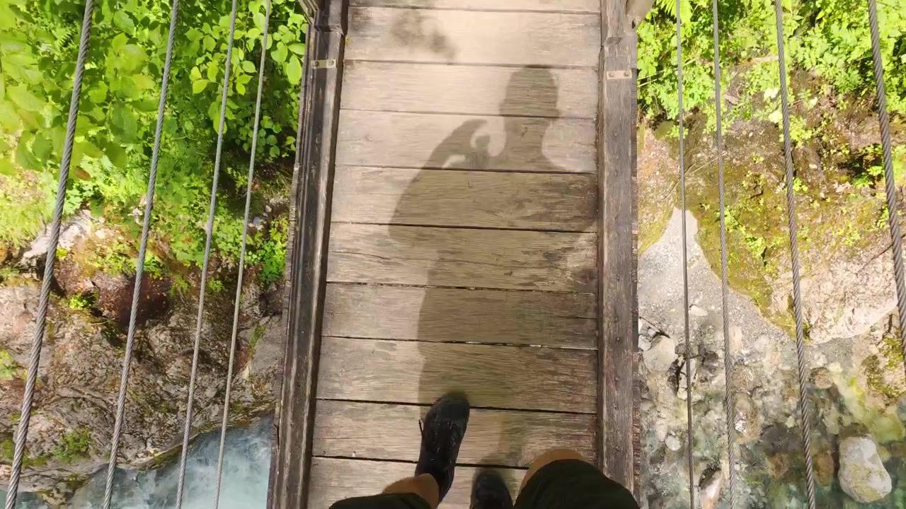 POV Crossing Wooden Suspension Bridge Above River Above Emerald River