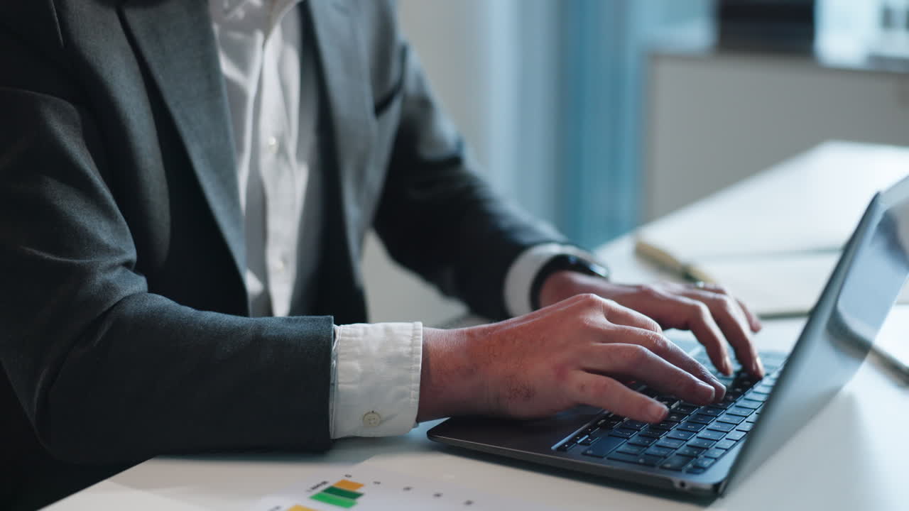 Profesjonell mann som jobber på bærbar PC ved kontorpulten.