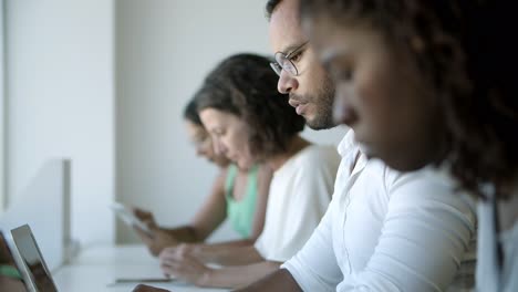 Focused-African-American-man-in-eyeglasses-typing-on-laptop