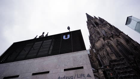 striking contrast between the historic cologne cathedral and a modern subway lift entry, showcasing the blend of old and new architecture in cologne, germany.