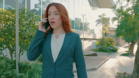 Close-up-shot-of-Caucasian-businesswoman-entrepreneur-walking-though-city-sidewalk-while-talking-phone-conversation-on-a-sunny-day