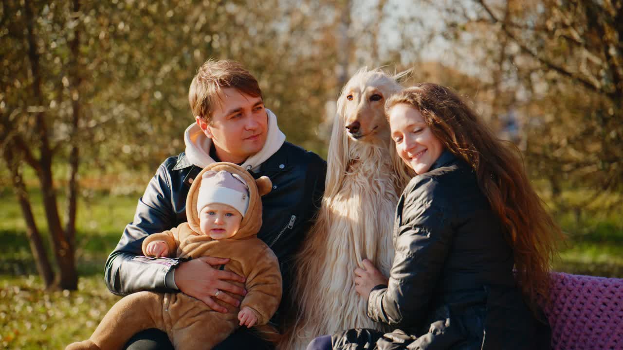 A Heartwarming Family Moment with a Baby, a Loving Couple, and Their Elegant Afghan Hound in a Serene Outdoor Setting Surrounded by Nature's Beauty
