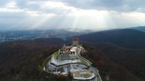 aerial view of castle on the hill with town and light rays shining in the background