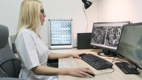una radióloga profesional examina los resultados de una tomografía computarizada o una resonancia magnética cerebral, trabajando en una pantalla de computadora en su escritorio personal en el hospital