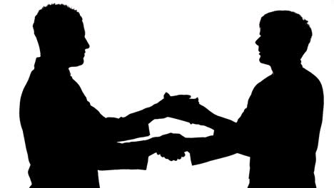 silhouette of businessmen shaking hands while passing a bribe