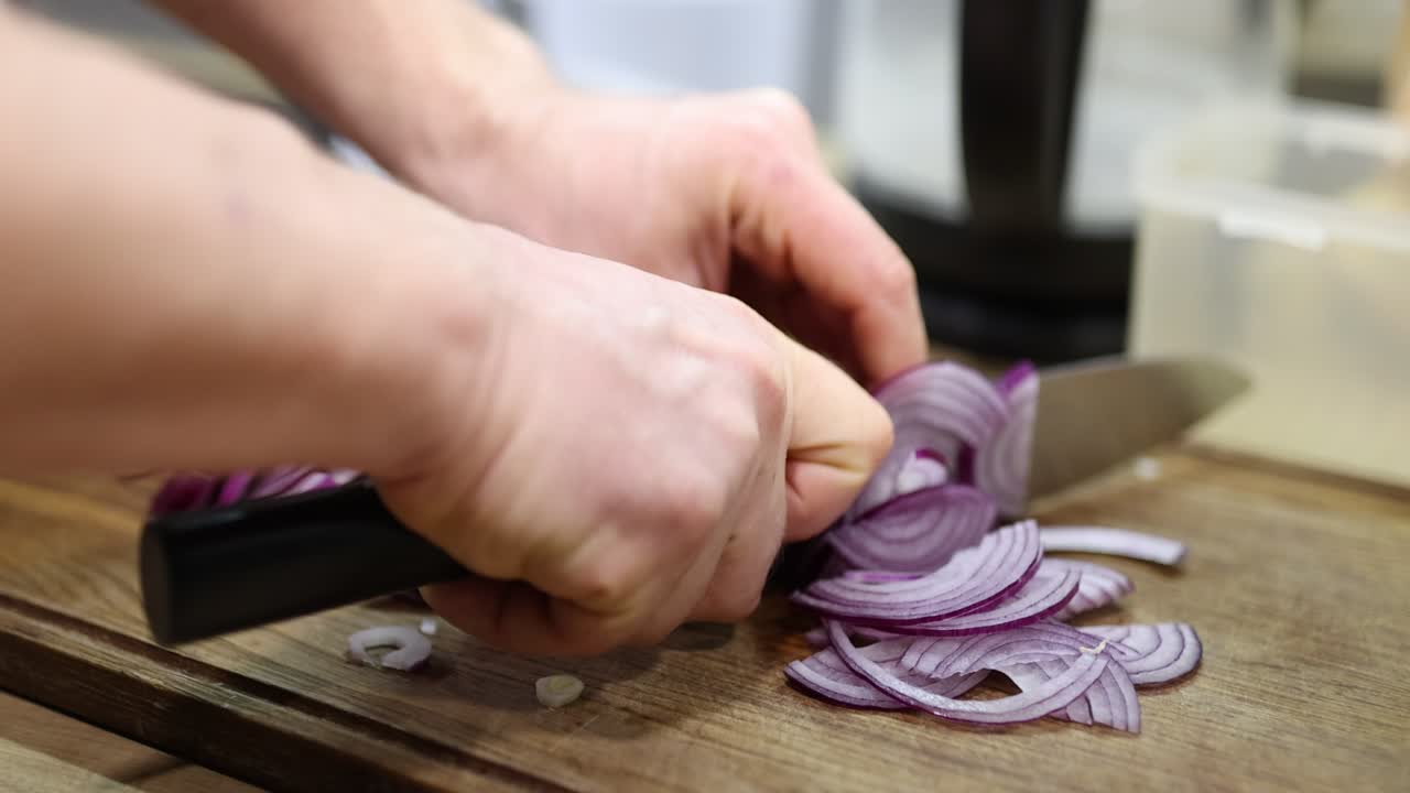Hands Slicing Red Onions on a Wooden Cutting Board