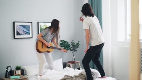couple having fun playing guitar and singing in bedroom