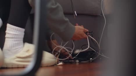 una persona en el hogar desenredando cables de energía eléctrica y cables de conexión para una computadora portátil u otro dispositivo electrónico