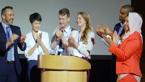 Business-people-applauding-at-podium-on-stage-in-auditorium-4k