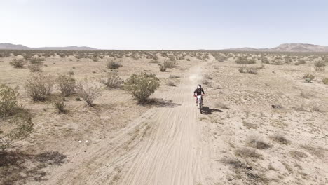 aerial: a dirt biker races on his honda crf motorcycle in the desert