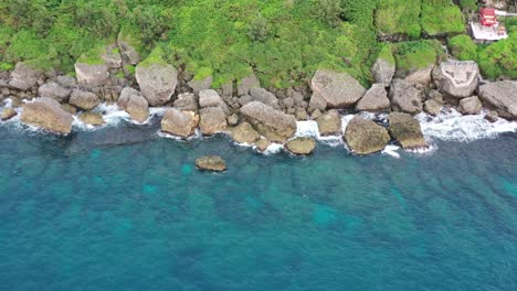 Aerial-pull-out-shot-away-from-the-rocky-coastal-shore-at-Xiaoliuqiu-Lambai-Island,-Pingtung-county,-Taiwan