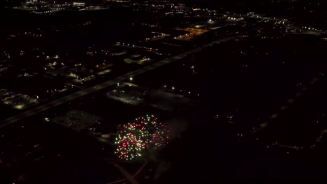 toma aérea de fuegos artificiales con luces de la ciudad en el fondo