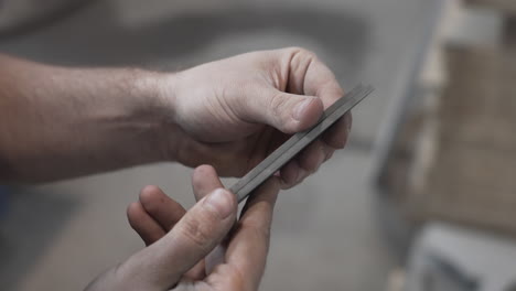 Edelstahlmessermuster-In-Der-Hand-Des-Handwerkers,-Messerfabrikprozess,-Nahaufnahme