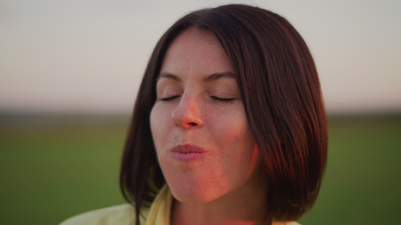 Caucasian woman tasting banana in field closeup for food review and social content, subtle smile while sampling peel and bite, golden dusk glow, meadow backdrop, casual influencer vibe, candid