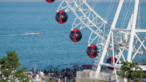 Sokcho-Eye-Ferris-Wheel-And-Sea-Beachline-Crowded-with-People-in-Sokcho-City,-South-Korea---Elevated-view