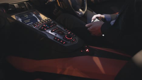 man using smartphone in a luxury car at night