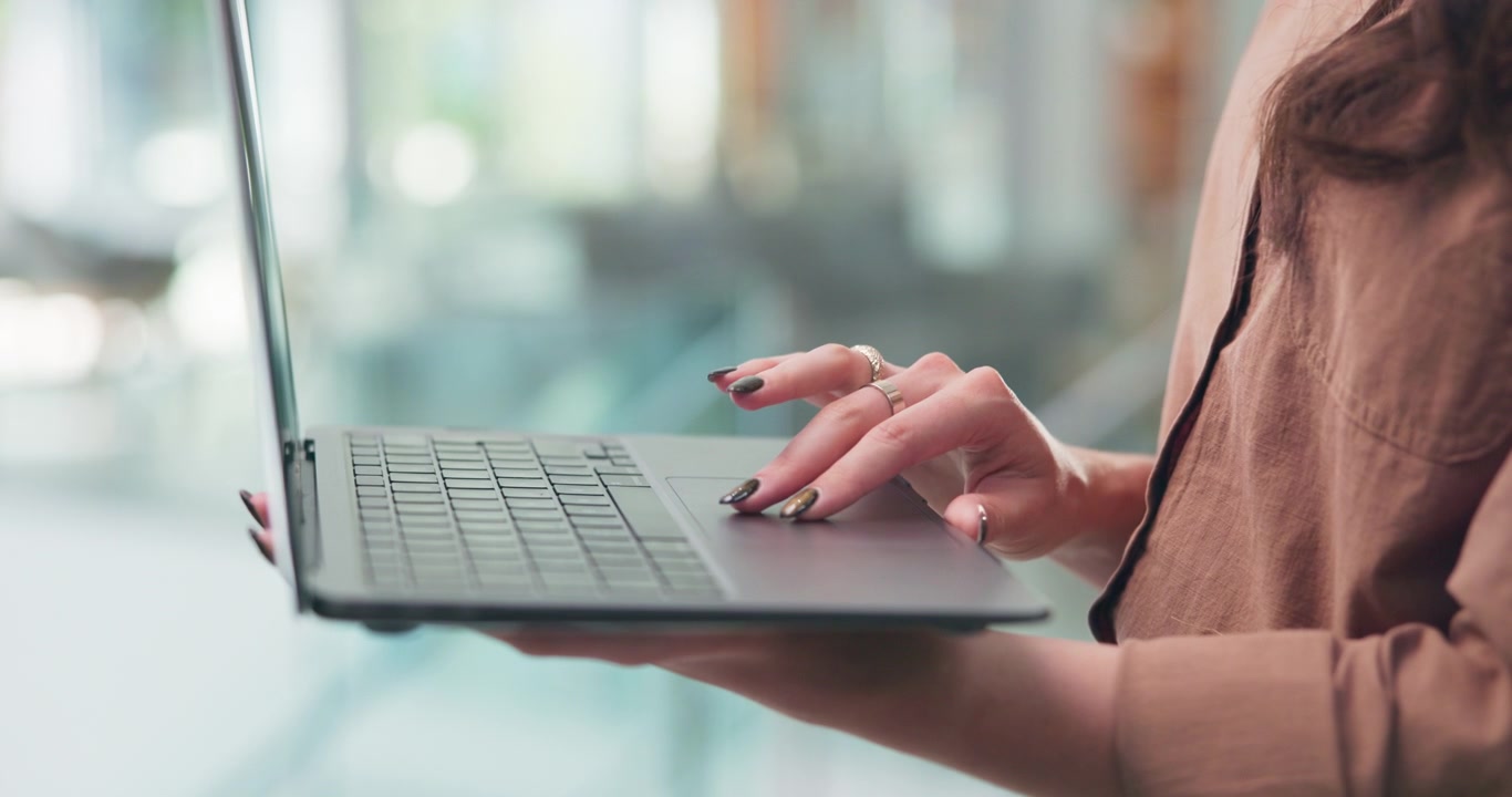 Kvinde bruger laptop-touchpad i lyst kontormiljø