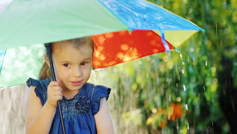 Fröhliches-Kleines-Mädchen-Von-Drei-Jahren,-Das-Unter-Einem-Regenschirm-Steht,-Der-Regen