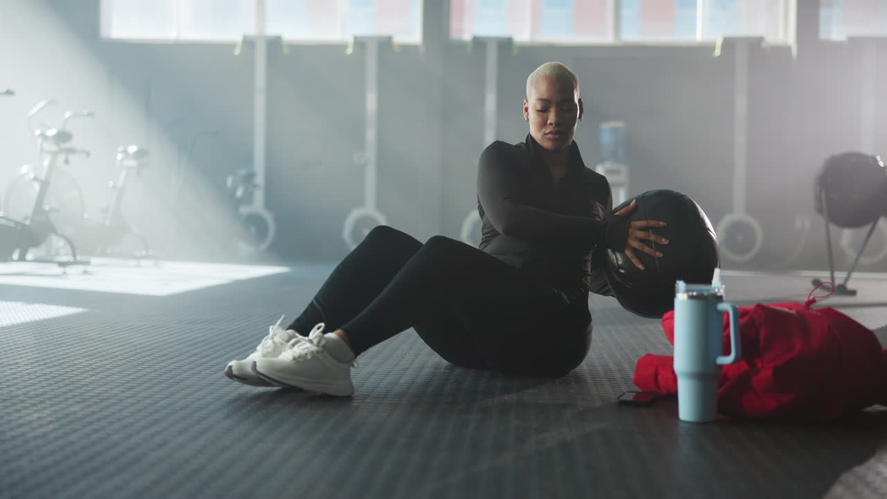 Wanita berolahraga dengan bola medicine di gym
