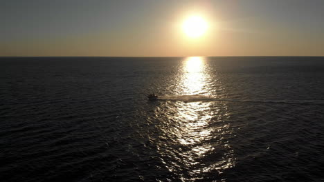 una mujer acelera en una moto de agua durante una hermosa puesta de sol con un océano vacío