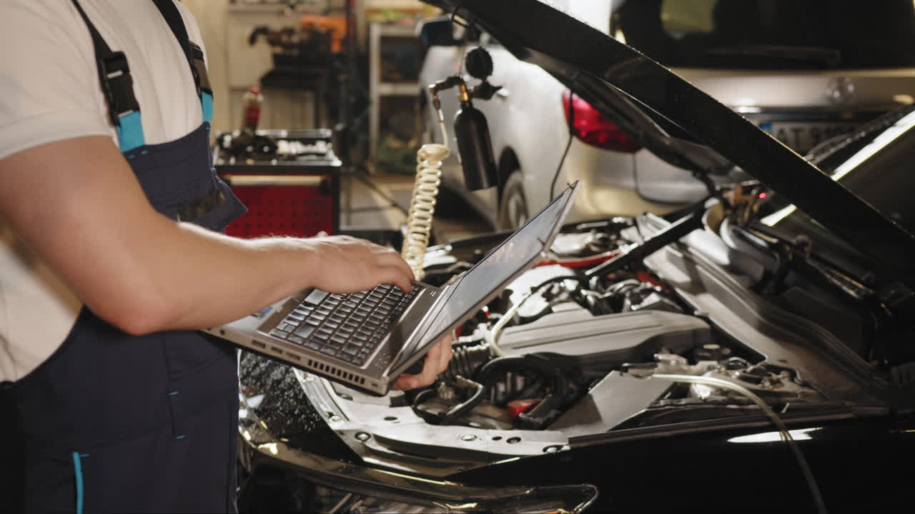 진단을 위해 노트북을 사용하는 자동차 메카닉