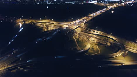 aerial drone eis fly above highway intersection, illuminated roads, cars, motorcycles, buses and trucks at night time in the modern, metropolitan city of warsaw, poland