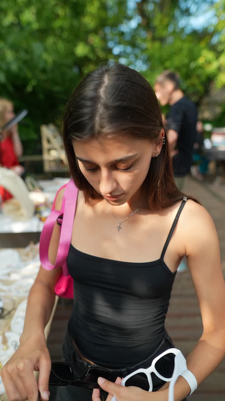 Giovane donna che acquista occhiali da sole in un mercato all'aperto
