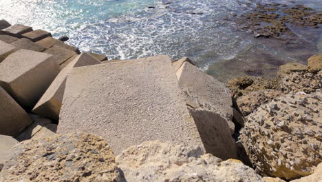 concrete breakwater blocks leading into a sparkling sea under a clear sky