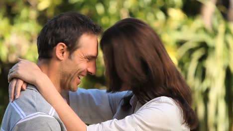 mujer abrazando a su marido y sonriendo a la cámara