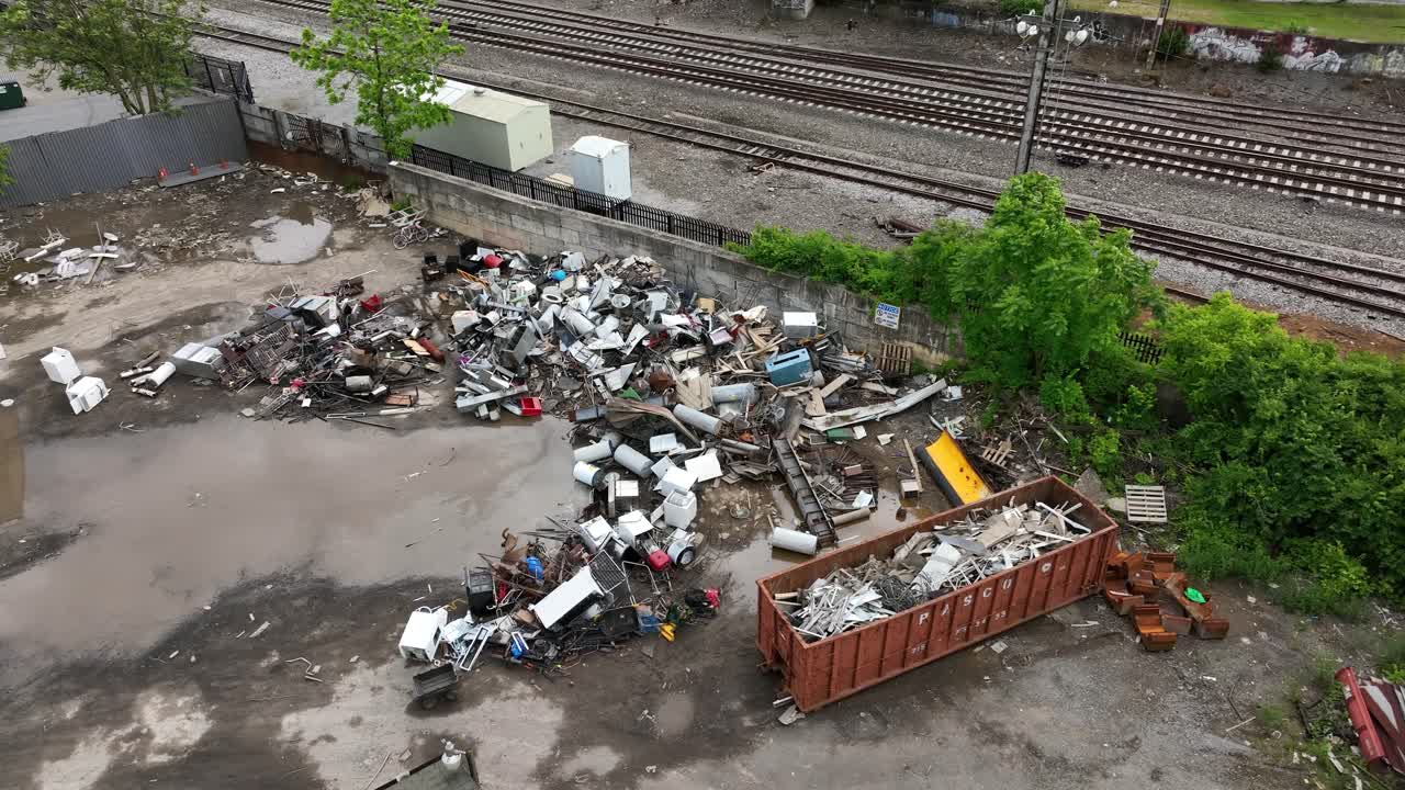 Aerial flyover junkyard beside rail roads in American city. Top down. Industrial company with rusty scarp.