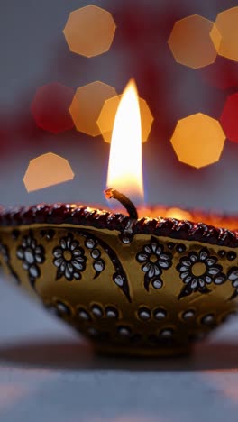 close-up of a decorative diya with a bright flame, captured at eye level