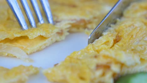 close-up of a knife cutting a plate of scrambled eggs