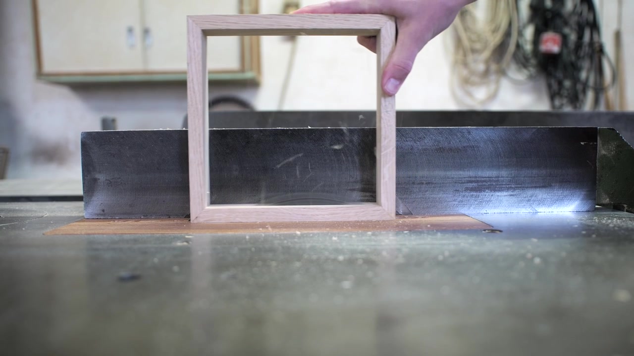 Falegname che taglia a metà una cornice di legno con sega circolare, vista laterale al rallentatore.