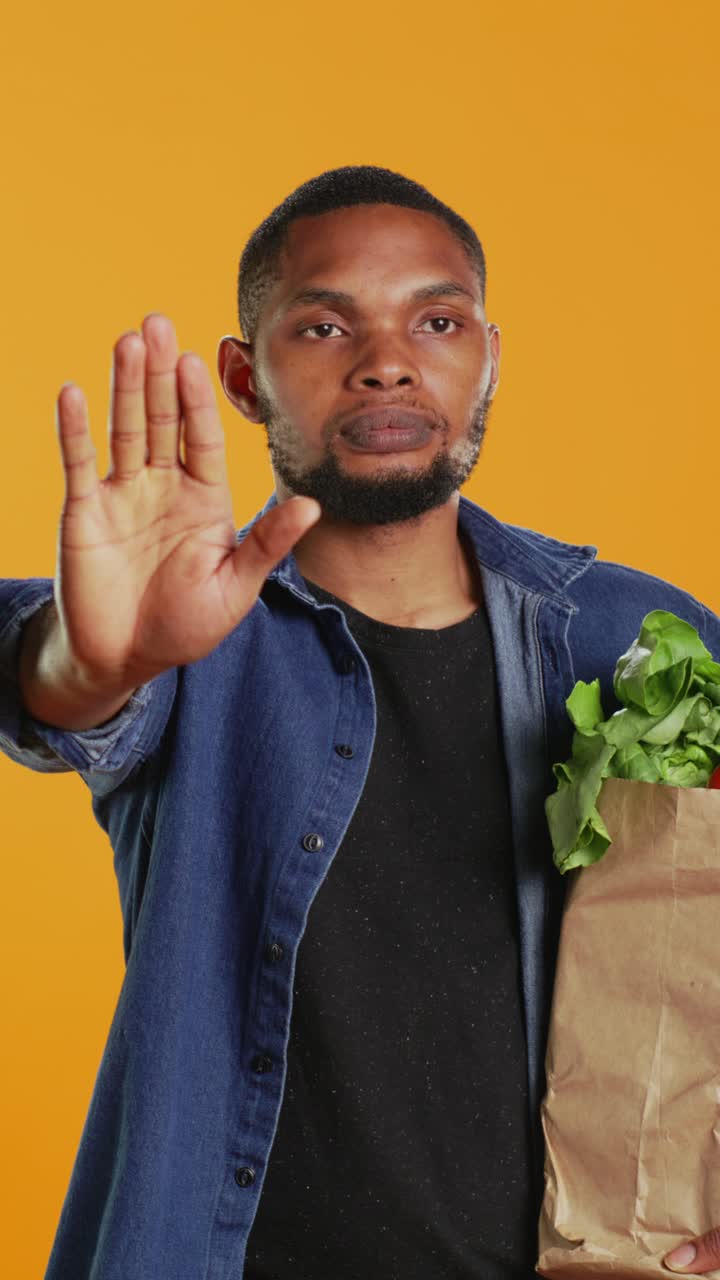 African American Man Holding Groceries Makes Stop Gesture
