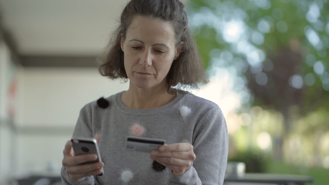 concentrada mujer de mediana edad con teléfono y tarjeta de crédito
