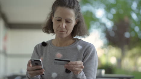 concentrada mujer de mediana edad con teléfono y tarjeta de crédito