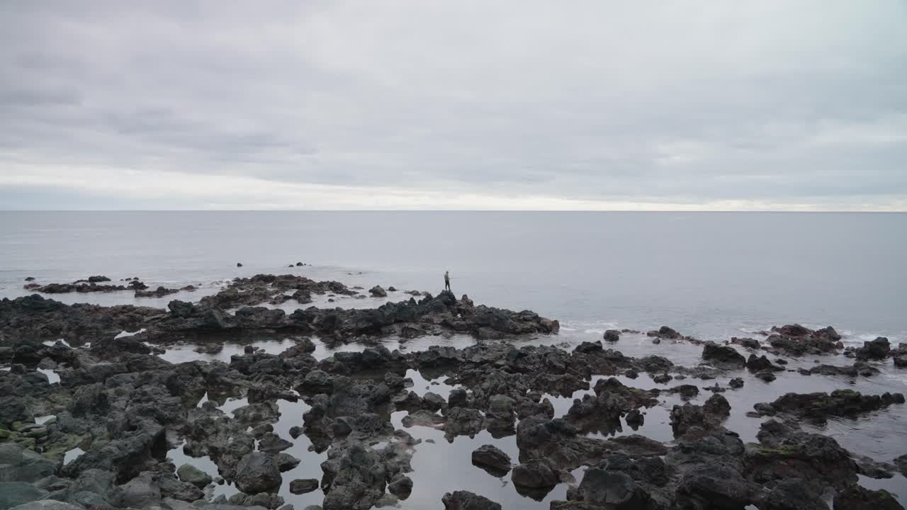 hombre pescando en una costa rocosa en ponta delgada, azores, portugal