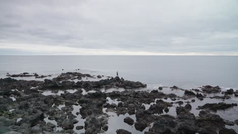 Man-fishing-on-a-rocky-shore-in-Ponta-Delgada,-Azores,-Portugal