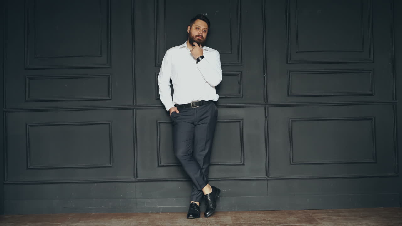 Uomo serio in studio. Giovane uomo barbuto, elegante e affascinante, in camicia bianca, in posa in studio.
