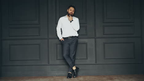 serious man in studio. stylish handsome young bearded man in white shirt posing in studio