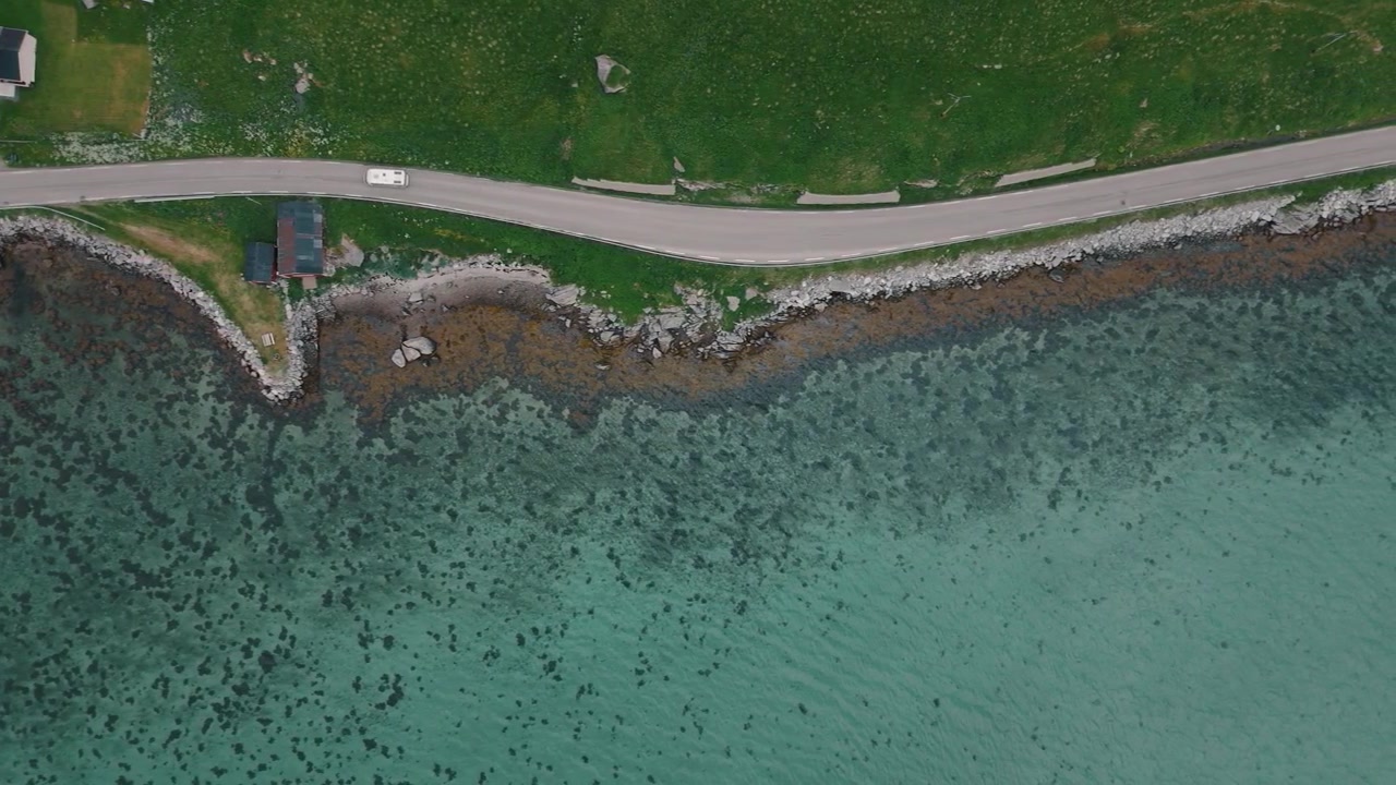 Biler følger en afsides kystvej langs klare Lofoten-farvande