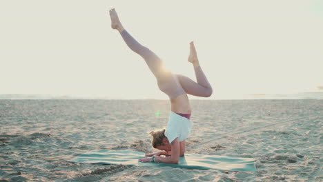 sportswoman doing yoga pose handstand with splits on the beach.