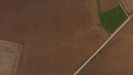 Sowing-fields-with-tractor-and-seeder-in-dusty-field-aerial-view