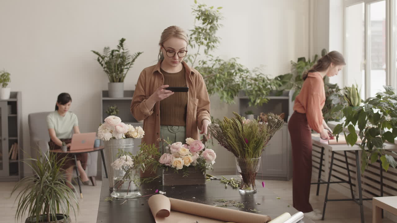 Florists taking photos of flower arrangements in a modern workplace