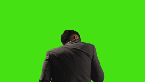 rear view of businessman talking on mobile phone against green screen background with low key lighting