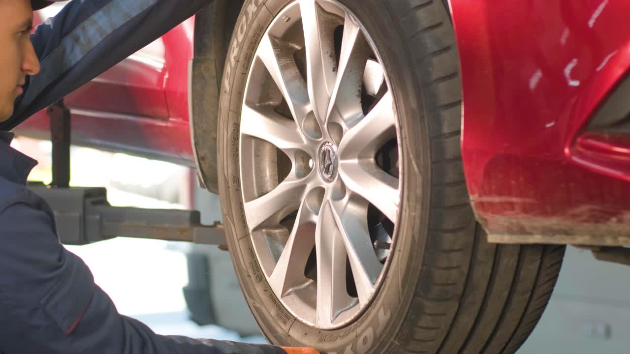 mecánico de automóviles reemplazando un neumático de automóvil en un taller de garaje. cámara lenta. servicio de automóviles